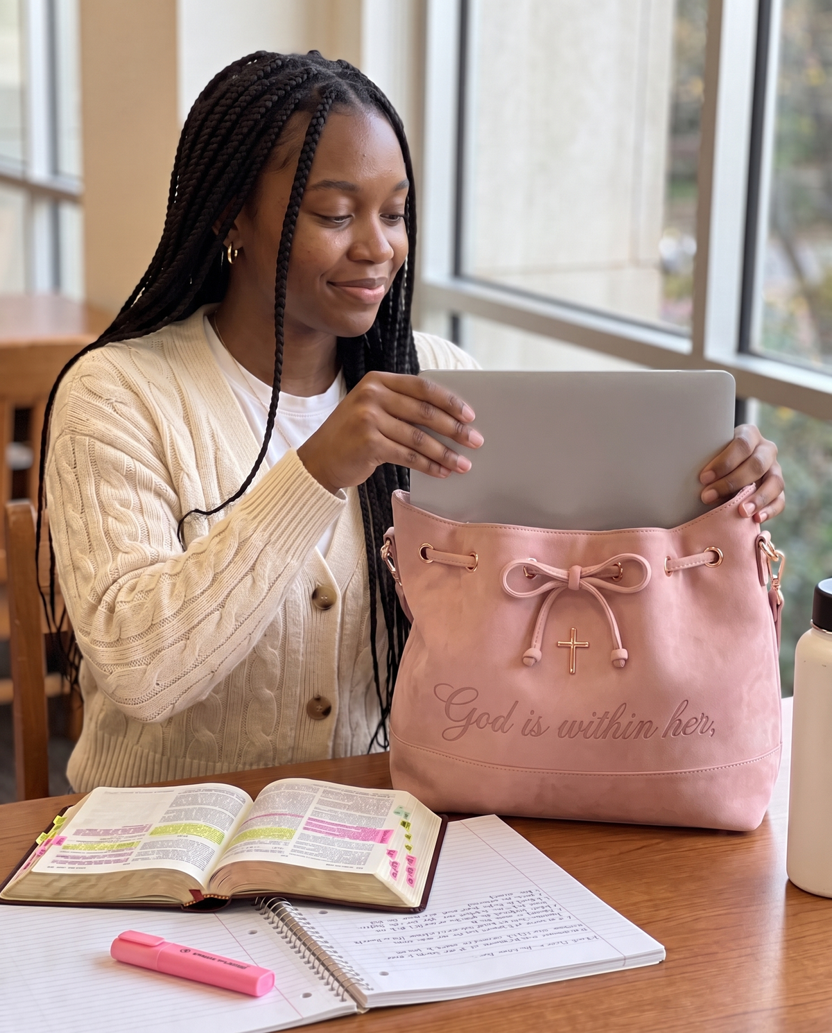 A student sliding her 14-inch laptop flat into the bag at a library table
